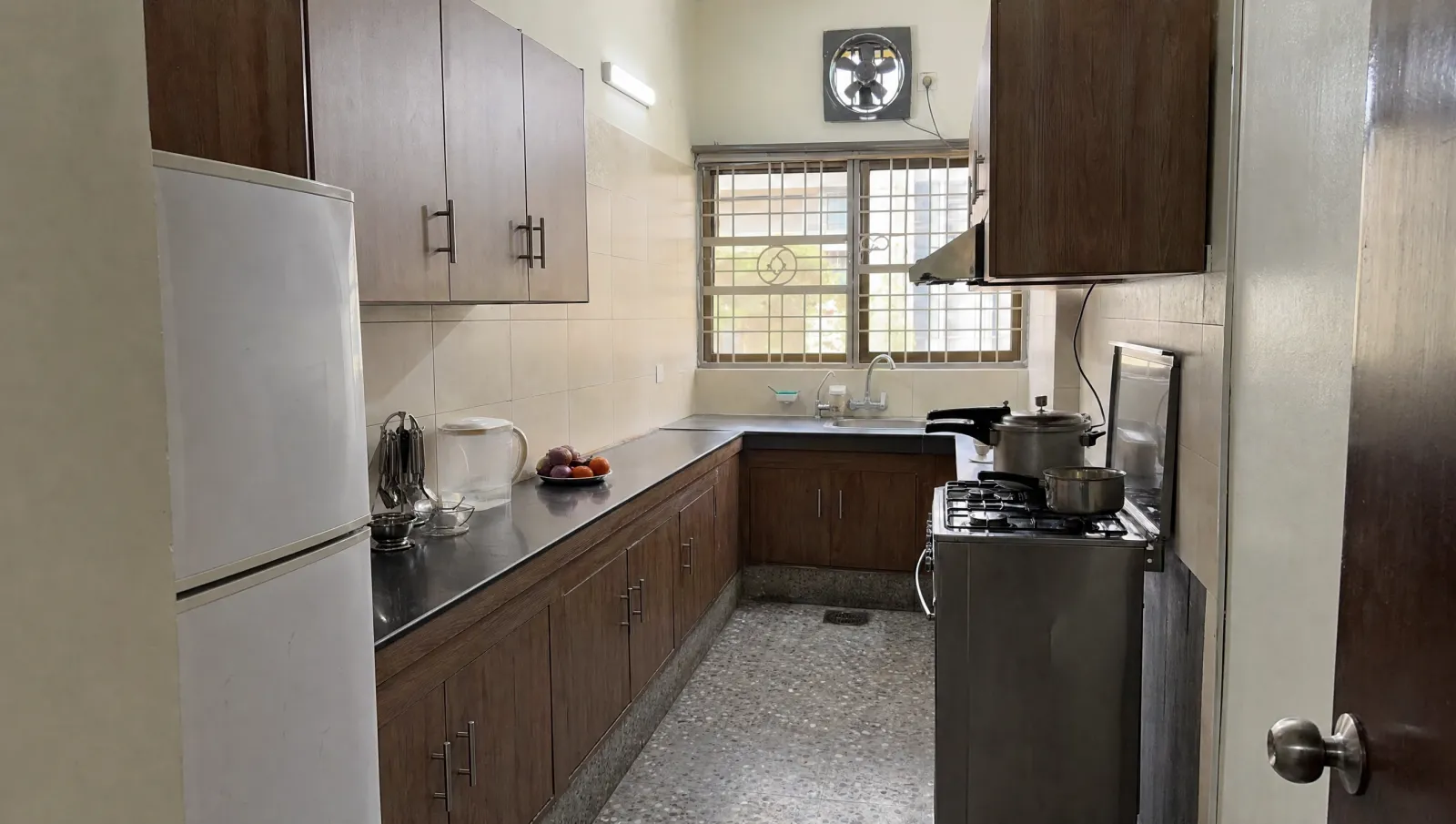 AI-generated illustration of a tidy, lived-in kitchen in a Karachi family flat.