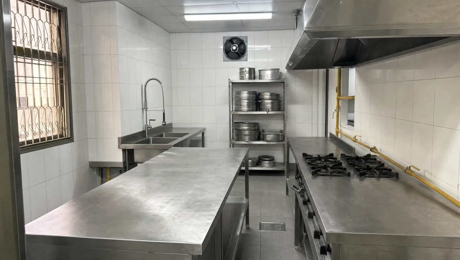 AI-generated illustration of a clean, empty stainless-steel staff kitchen with white tiled walls.